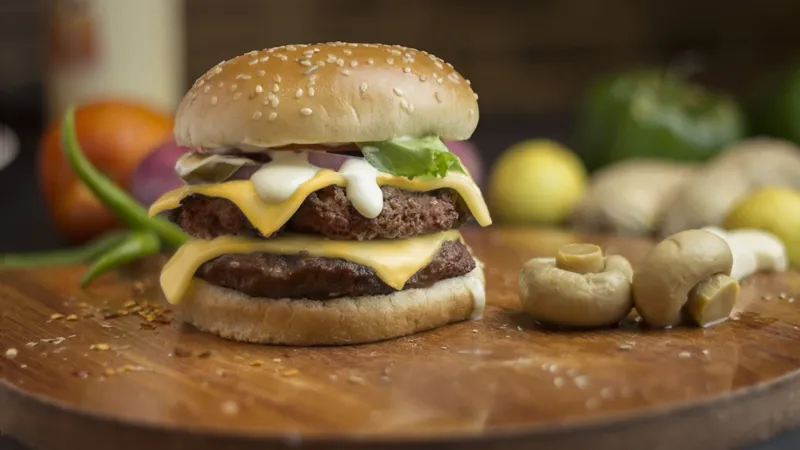 Delicious cheeseburger on a wooden board, topped with fresh mushrooms and vegetables.