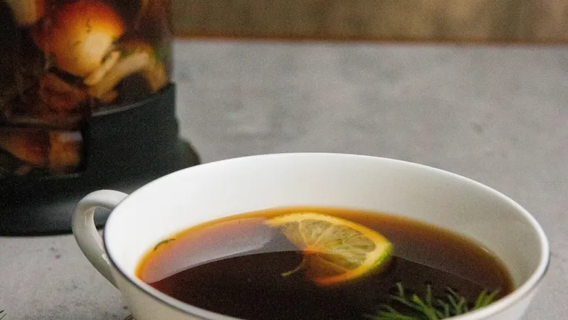 Close-up of a functional mushroom tea cup with a lemon slice and herbs on a saucer.