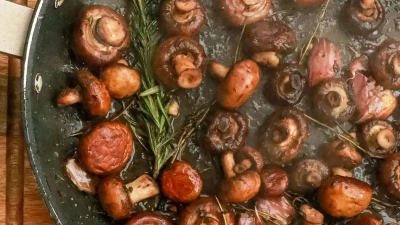 Delicious sautéed mushrooms with fresh herbs in a pan, perfect for a gourmet meal.