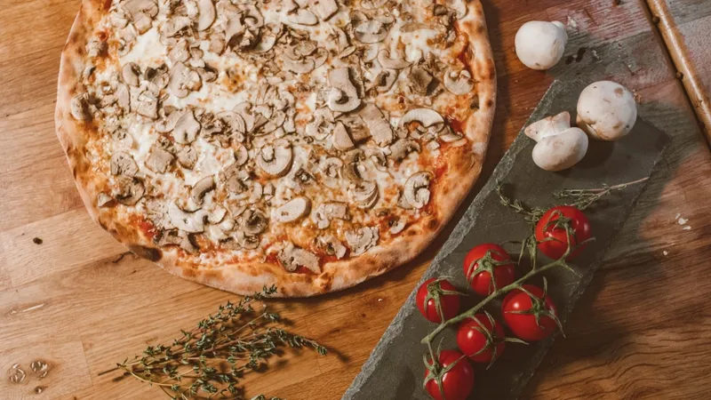 Appetizing pizza with mushrooms and tomatoes on rustic wooden table, perfect for vegetarian food enthusiasts.
